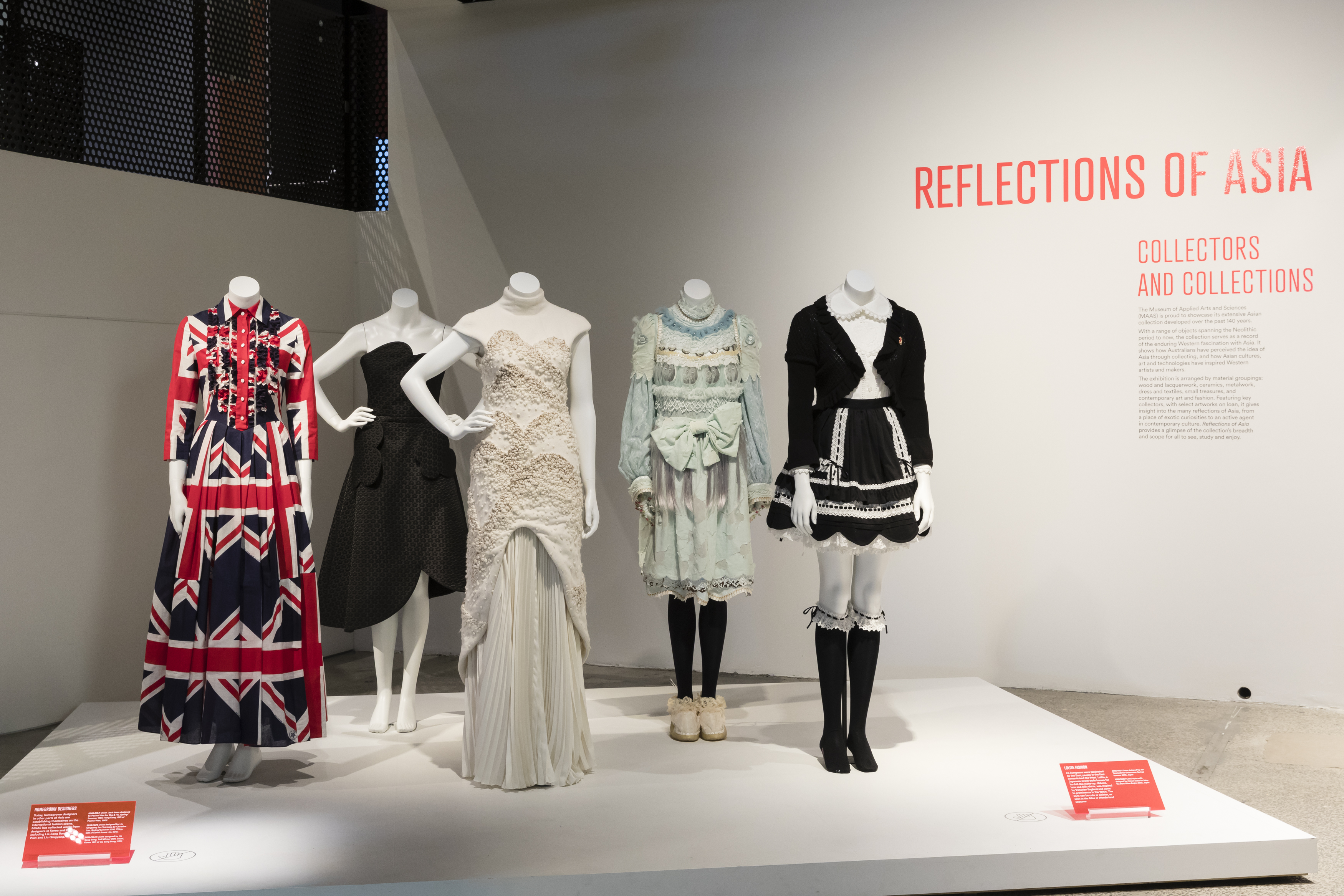 Exhibition view of an open display of contemporary fashion items on five mannequins. There are Victorian style outfits and a dress with Union Jack design.